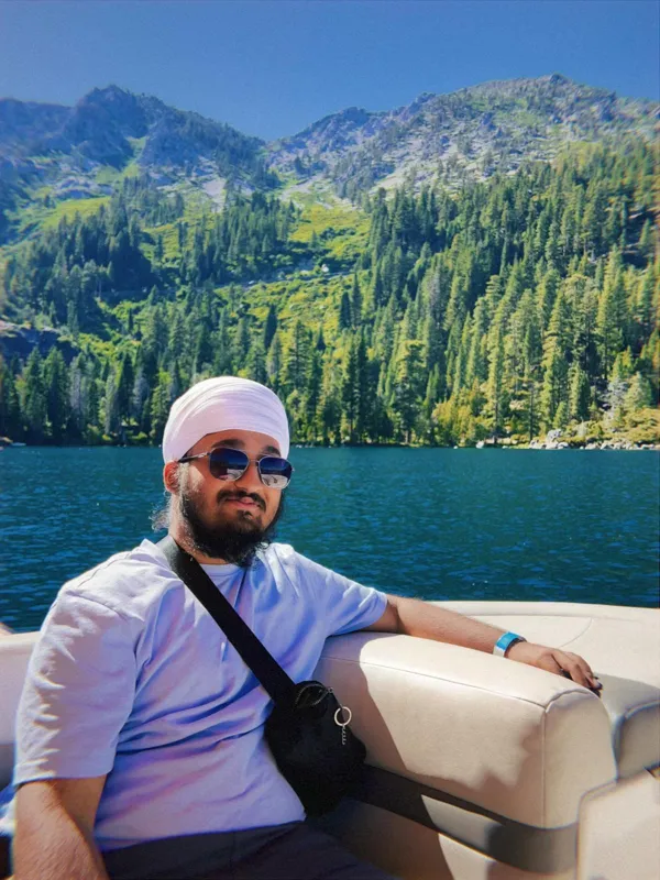 Keerat on a boat on a mountain lake, smiling in sunglasses