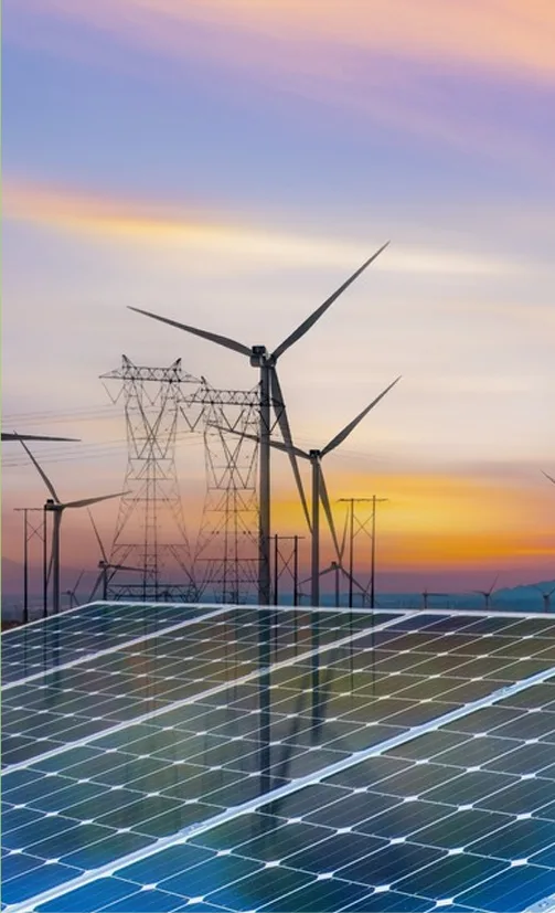 Wind turbines and solar panels at sunset